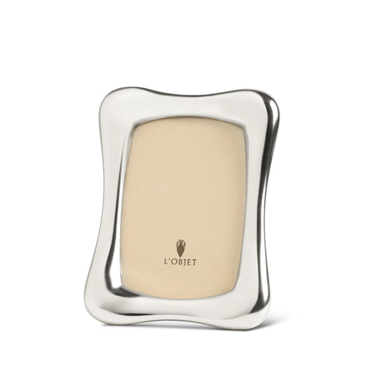 The Anton Frame Platinum by L’Objet is a luxury photo frame with wavy, curved edges, a beige insert featuring the brand logo, and an elegant modern design—perfect for displaying your treasured memories upright.