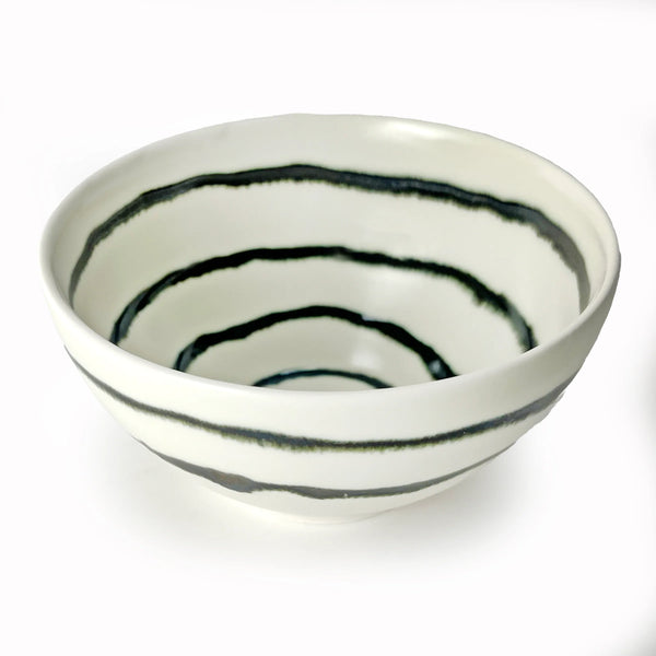 The Michael Wainwright Linea Dip Bowl features uneven, hand-painted black concentric stripes adorning both the interior and exterior of its white ceramic form, shown here against a white background.