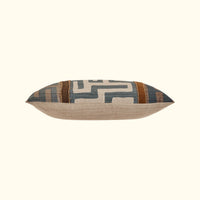 The Kasai Pillow 16 x 24 by Threads Soft Goods features a handcrafted geometric Kuba cloth design in muted blue, beige, and brown. Shown with a plain light background, this rectangular pillow adds decorative flair to any space.