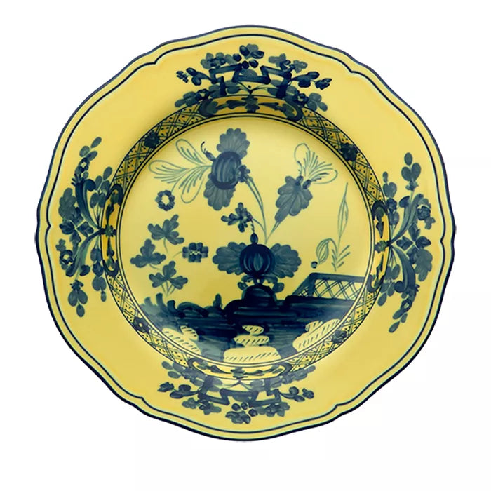A round, yellow porcelain plate from the Ginori 1735 Oriente Italiano Dinnerware Citrino collection, featuring ornate blue chinoiserie floral motifs and geometric accents along the rim and center, reminiscent of classic Italian porcelain, viewed from above.