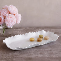 A Beatriz Ball Vida Colette Melamine Platter White - Large displays four colorful macarons on a gray countertop beside a vase of pink peonies.
