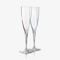 Two clear, empty glass Dom Perignon Champagne Flutes by Baccarat are standing side by side on a white background, evoking the elegance of classic crystalware.