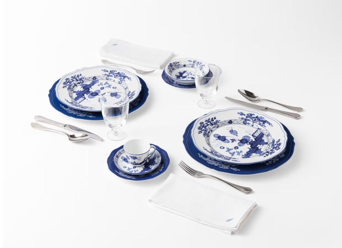 Two place settings featuring Ginori 1735 Oriente Italiano Indaco - porcelain dinnerware with intricate blue floral patterns, arranged with silverware, glassware, and white napkins.