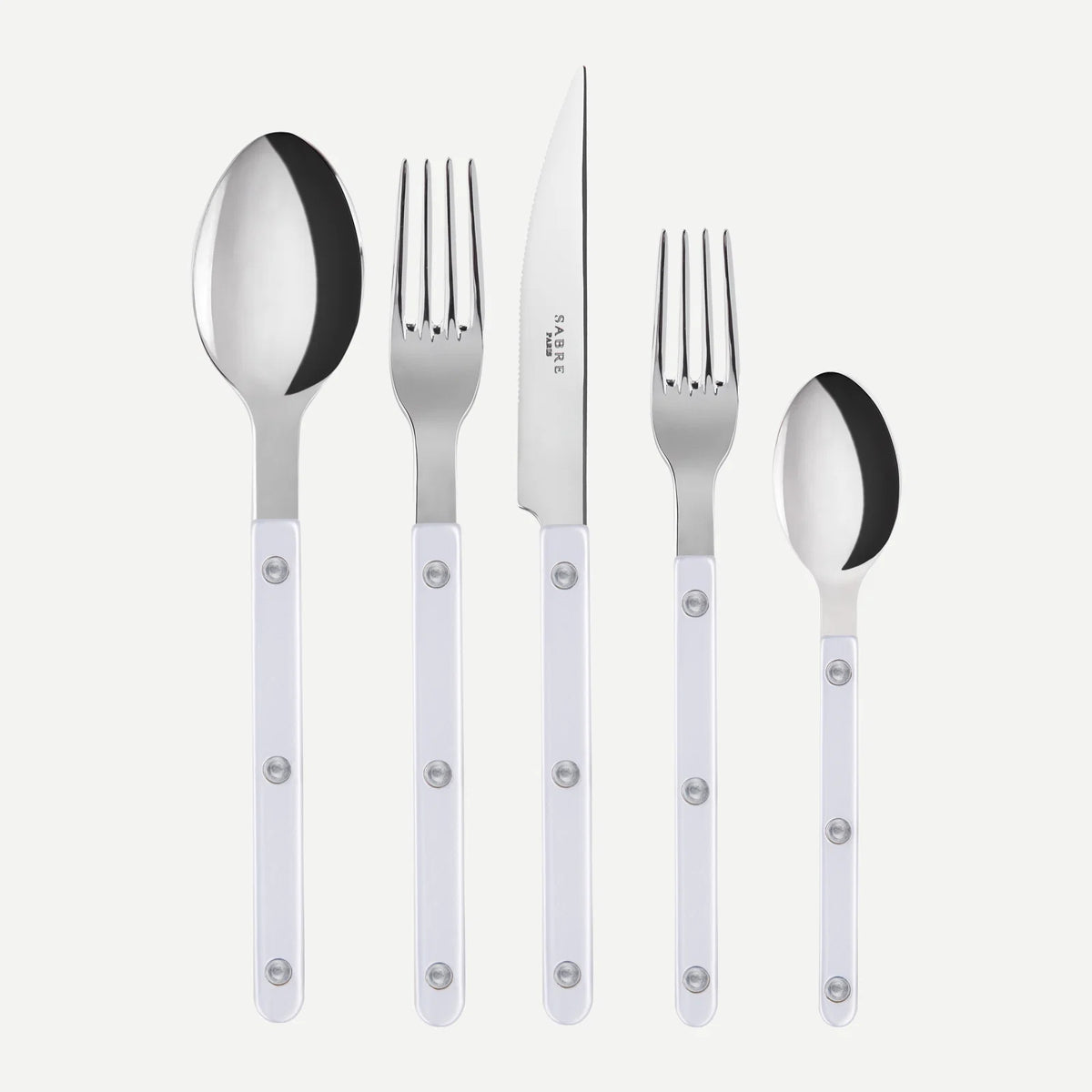 The Sabre Bistrot Pearly 5 Piece Setting - Shiny, part of the renowned Bistrot collection and expertly crafted in France, features a tables­poon, table fork, dinner knife, salad fork, and teaspoon. Each piece boasts a shiny metal head paired with an elegant mother of pearl handle adorned with three silver rivets. The set is artfully arranged in a row against a white background, embodying timeless style and exceptional craftsmanship.