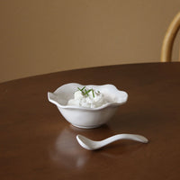 A small white bowl topped with whipped cream and chives sits on a wooden table beside a stylish, BPA-free Beatriz Ball Vida Havana Spoon - Mini, made of dishwasher-safe melamine.
