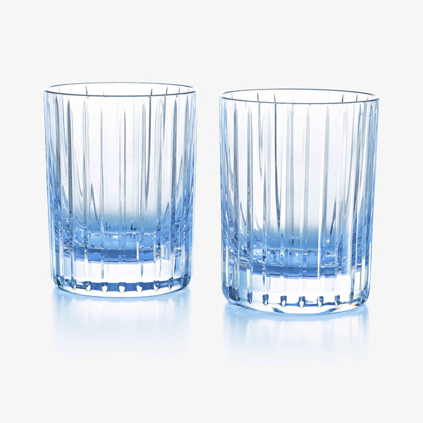 The Harmonie Colors of Joy Set of 2 in Pastel Blue by Baccarat features two crystal tumblers with elegant vertical ridges, perfectly paired side by side on a white background—an ideal stylish addition to your glassware collection.