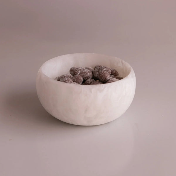 The Beatriz Ball Resin Sorbet Mini Bowl - Coconut holds cocoa-dusted chocolate almonds and rests on a smooth, light-colored surface with a plain background.