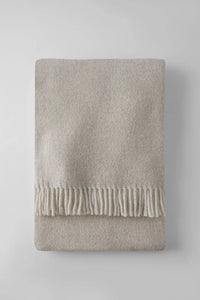 The A Soft Idea Tweed Weave Throw, in a neatly folded beige style with a fringe on one edge, is displayed on a light gray surface.