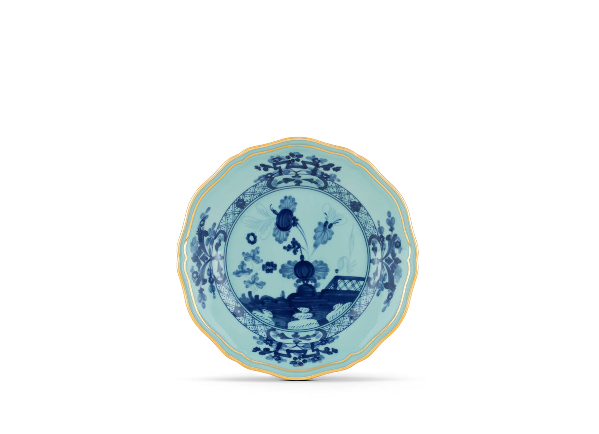 Oriente Italiano Dinnerware Iris by Ginori 1735 is a blue and white porcelain plate with a scalloped, gold-trimmed edge, adorned with an intricate chinoiserie floral motif inspired by Ginori Oriente in the center and along the rim, all set against a plain white background.