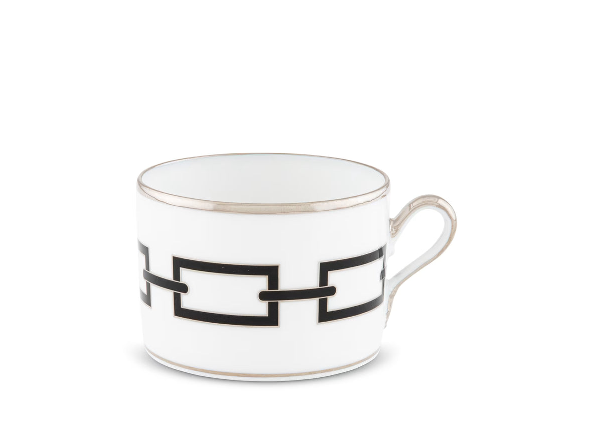 The Ginori 1735 Catene Nero teacup is crafted from white porcelain and accented with a silver rim and handle, showcasing a striking black geometric chain-link rectangle pattern around its side, photographed against a plain white background.