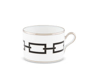 The Ginori 1735 Catene Nero teacup is crafted from white porcelain and accented with a silver rim and handle, showcasing a striking black geometric chain-link rectangle pattern around its side, photographed against a plain white background.