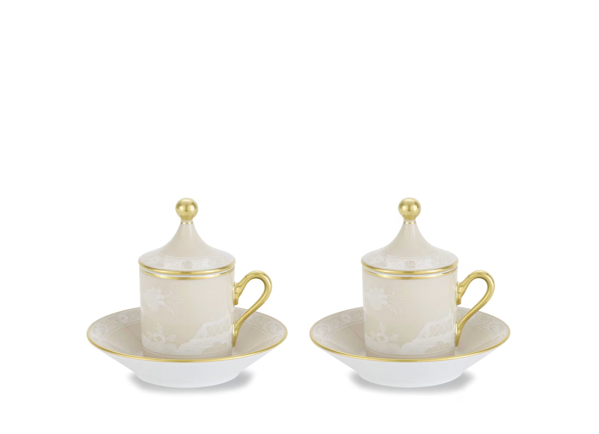 Two lidded Oriente Italiano Beige Meringa espresso cups on matching saucers by Ginori 1735, featuring a beige floral pattern, gold handles, and gold finials.