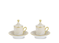 Two lidded Oriente Italiano Beige Meringa espresso cups on matching saucers by Ginori 1735, featuring a beige floral pattern, gold handles, and gold finials.