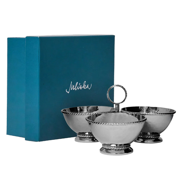 The Juliska Graham Triple Cocktail Bowl features three hammered stainless steel bowls with a decorative edge, one with a loop handle, elegantly displayed in front of a teal Juliska box.