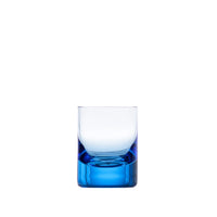 The Moser Whiskey Set Shot Glass is a clear glass tumbler with a thick blue base, displayed against a plain white background and crafted from hand-blown glass for an elegant finish.