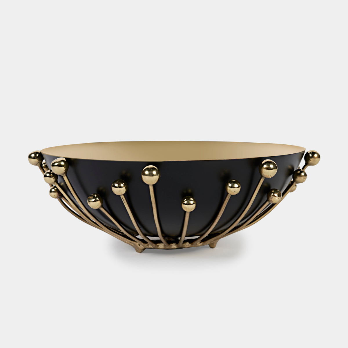 The Eden Bowl by Luho features a modern matte black exterior, a gold interior, and gold spheres connected by rods radiating from the base. This food-safe accessory blends striking design with everyday functionality.