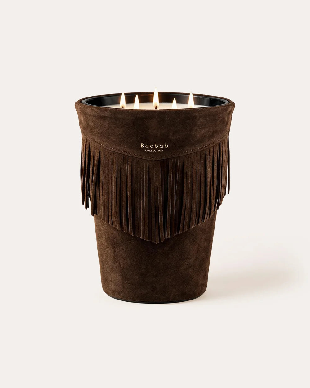 A dark brown, four-wick Baobab Calamity Jane Candle - Deadwood with fringe detailing around the rim, shown with the wicks lit.