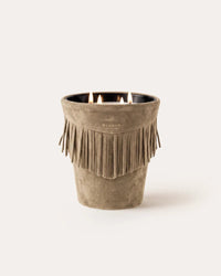 A lit three-wick Baobab Calamity Jane Candle - The Plains in a mineral taupe leather, tan, fringe-trimmed suede vessel.