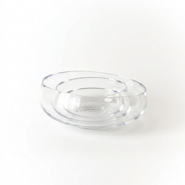 The Gary Bodker Nesting Bowl Collection Clear features three hand-blown clear bowls, elegantly nested together on a white surface with a minimalist background.