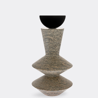 The Gardeco Constantin Gray w/ Black Sculpture features two stacked, geometric stone shapes with a textured gray-brown finish, topped by a smooth black half-sphere. Its modernist design makes it ideal for contemporary home decor. Displayed against a plain white background.