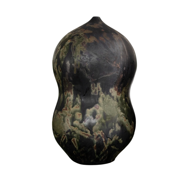 The Devenir 2 Vase by CDMX / MASA TALLER is a handcrafted piece featuring a curvy silhouette and a dark, mottled glaze in black, green, and brown tones, giving this sculptural object an organic and natural appearance.