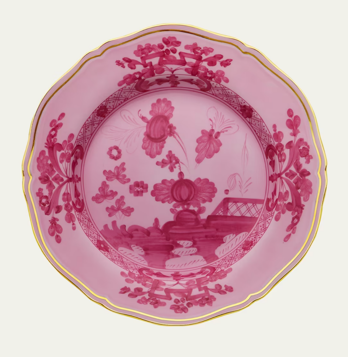 The Oriente Italiano Porpora plate by Ginori 1735 features an intricate chinoiserie floral motif in pink porcelain, with gold trim accenting its scalloped edge, viewed from above on a white background.