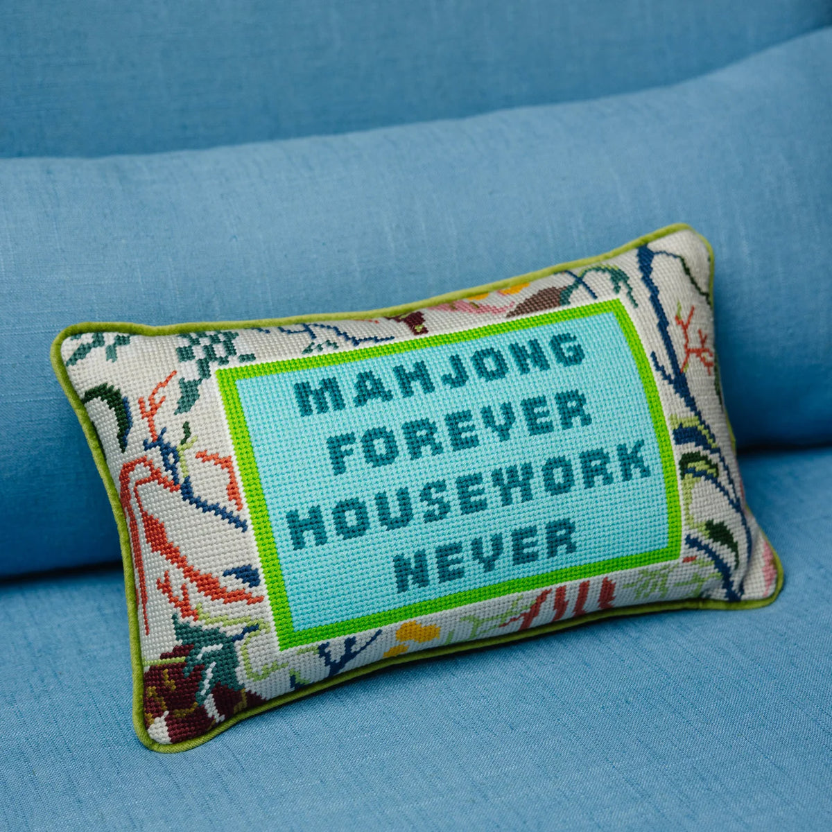 The Needlepoint Pillow - Mahjong by Furbish features floral embroidery and a blue panel with "MAHJONG FOREVER HOUSEWORK NEVER"—an ideal decorative gift for any Mahjong fan.