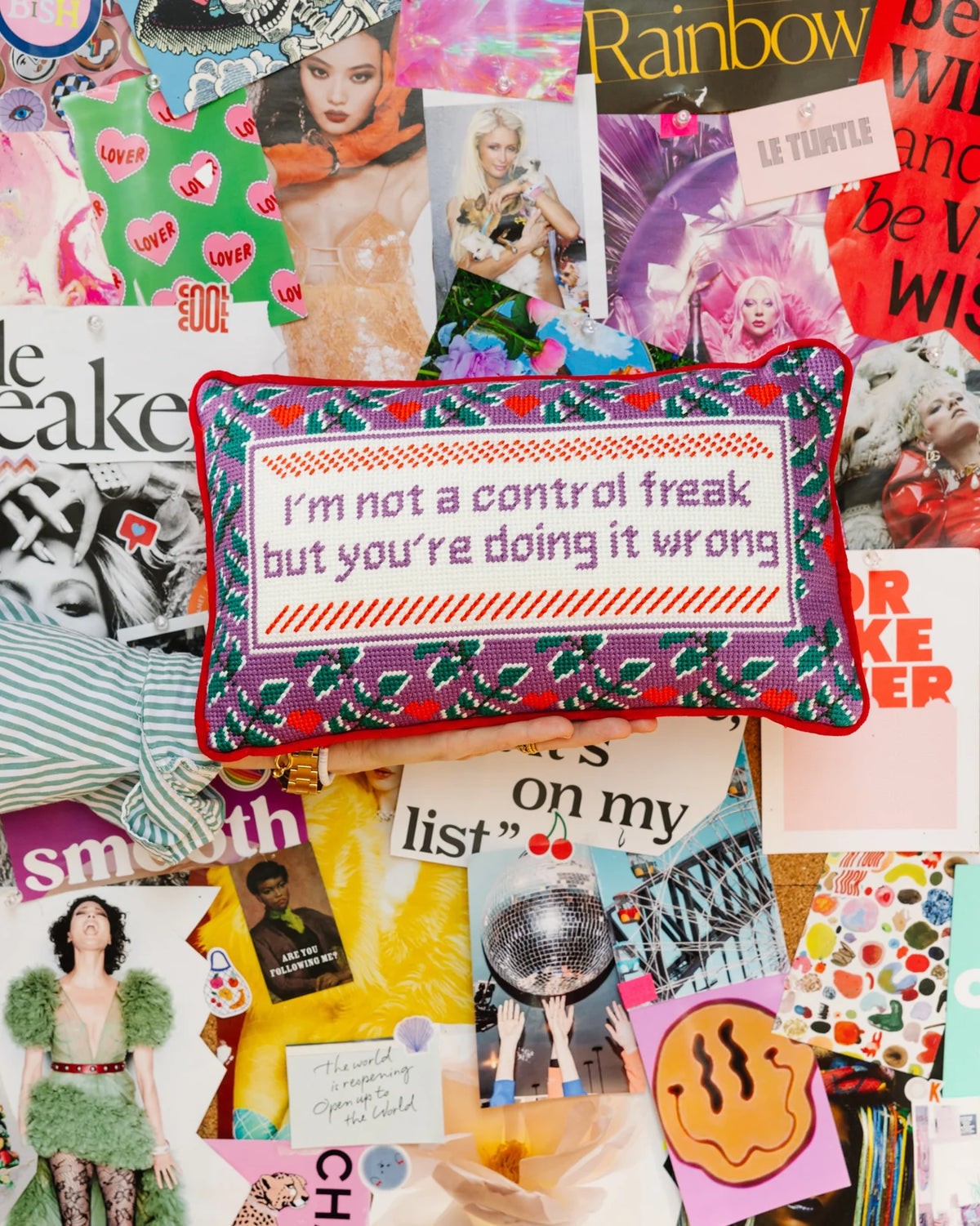 A vibrant bulletin board displays magazine cut-outs and stickers. At the center sits Furbish's Needlepoint Pillow - Control Freak, featuring the playful phrase: "I'm not a control freak but you're doing it wrong.