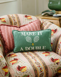 The Furbish Needlepoint Pillow - Make It A Double features green fabric, white text, and tennis rackets, making it a charming gift for tennis lovers who appreciate unique decor.