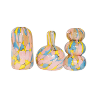The Jelly Baby Mini Vase Collection by Maria Ida Designs features three handmade art glass blown mini vases in abstract shapes, each adorned with pastel pink, blue, yellow, and gray streaks—arranged side by side on a white background for unique home decor.