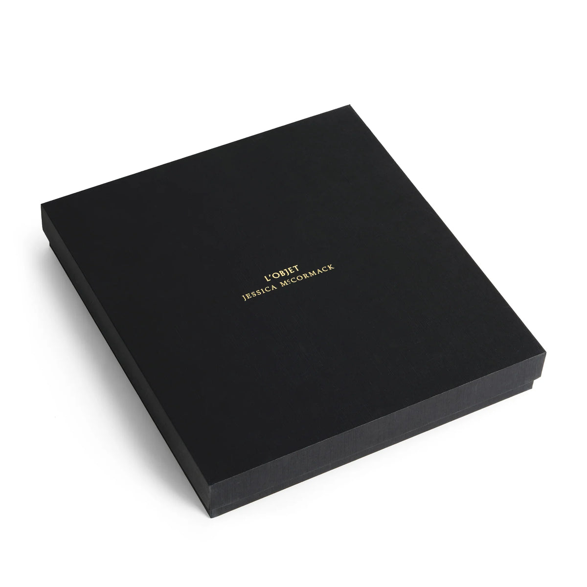 A square black gift box featuring the gold-stamped text L’OBJET JESSICA MCCORMACK on the lid, housing a Jessica McCormack Shell Flatware 5 pc Set - Gold.