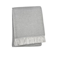 The Grain of Rice Throw by A Soft Idea is a folded light gray soft blanket with an ivory fringe, displayed on a plain white background. This machine washable throw adds comfort and style to any space.