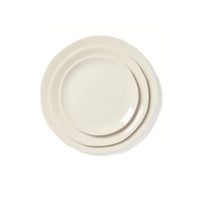 Three off-white ceramic plates from the Maguelone Dinnerware Quartz collection by Jars - Rosenthal, each a different size, are stacked together on a white background. Every plate features an irregular, organic-shaped edge, beautifully reminiscent of Mediterranean dinnerware.