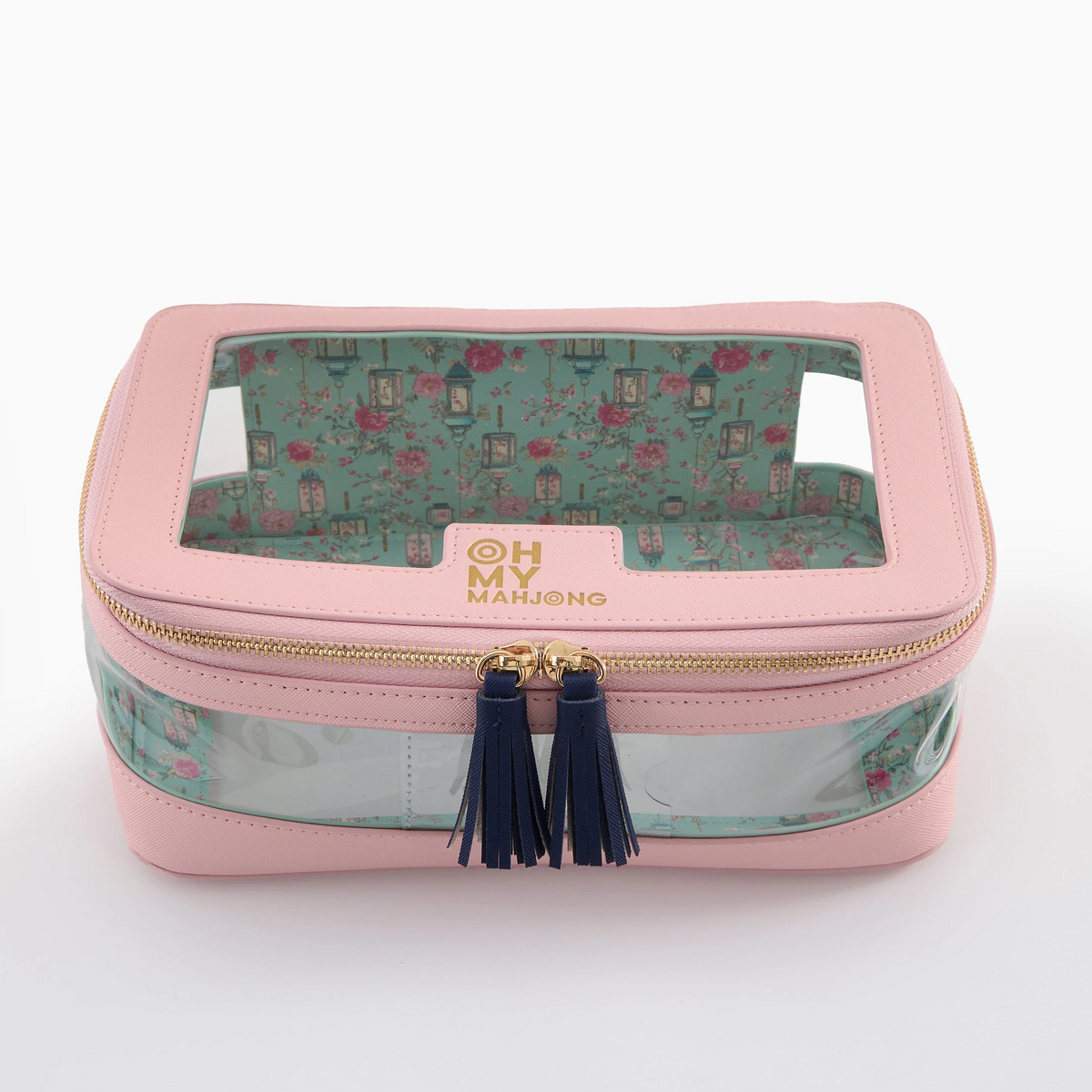 A stylish Mahjong Tile Storage Bag by Oh My Mahjong, featuring a pink exterior, clear top window, gold zipper, navy tassels, and a floral-patterned interior. The front is adorned with “OH MY MAHJONG” printed in gold, making this chic case an ideal organizer for effortless Mahjong tile storage.