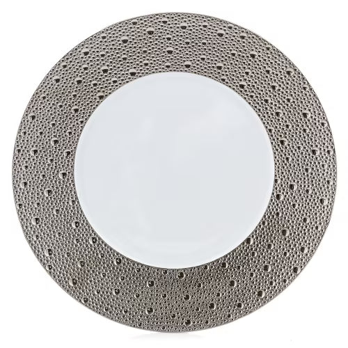 A white plate from the Bernardaud Ecume Platinum Dinnerware collection, featuring a wide, textured metallic rim adorned with a pattern of raised dots reminiscent of craters or bubbles—perfect for adding a touch of contemporary elegance to any table setting.