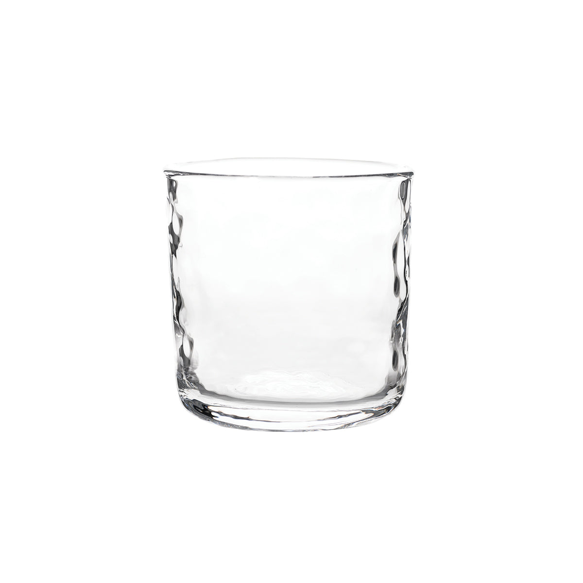 A clear, empty glass tumbler from Juliska’s Puro Glassware collection, featuring a subtly textured surface, is set against a plain white background.