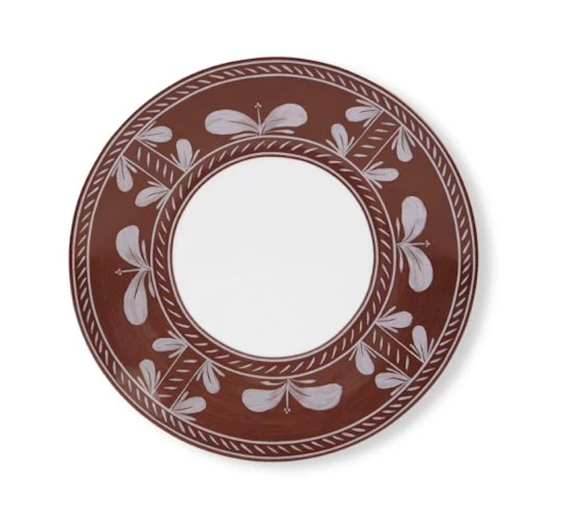 Round Sevilla Dinnerware Brown Limoges porcelain dinner plate with a white center and a brown rim decorated with a repetitive light grey floral pattern.