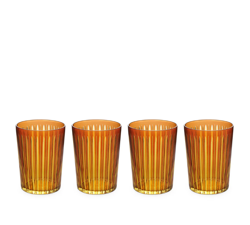 The Prism Highball Set of 4 by L'Objet features amber-colored glasses with vertical ribbed patterns. These stylish, dishwasher-safe tumblers are arranged in a row against a white background, combining elegance and convenience for everyday use.