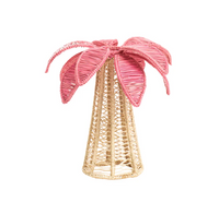 The Coro Cora Palm Tree Table Accent - Light Pink - Small features a handcrafted beige trunk and large pink leaves, creating a festive, decorative centerpiece. It's displayed against a plain white background.