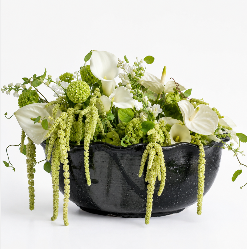 A Leona Bowl - Marina by CDMX / MASA TALLER, filled with white calla lilies, green amaranthus, viburnum, and other green and white flowers, is arranged elegantly against a white background to create a stunning decorative piece.