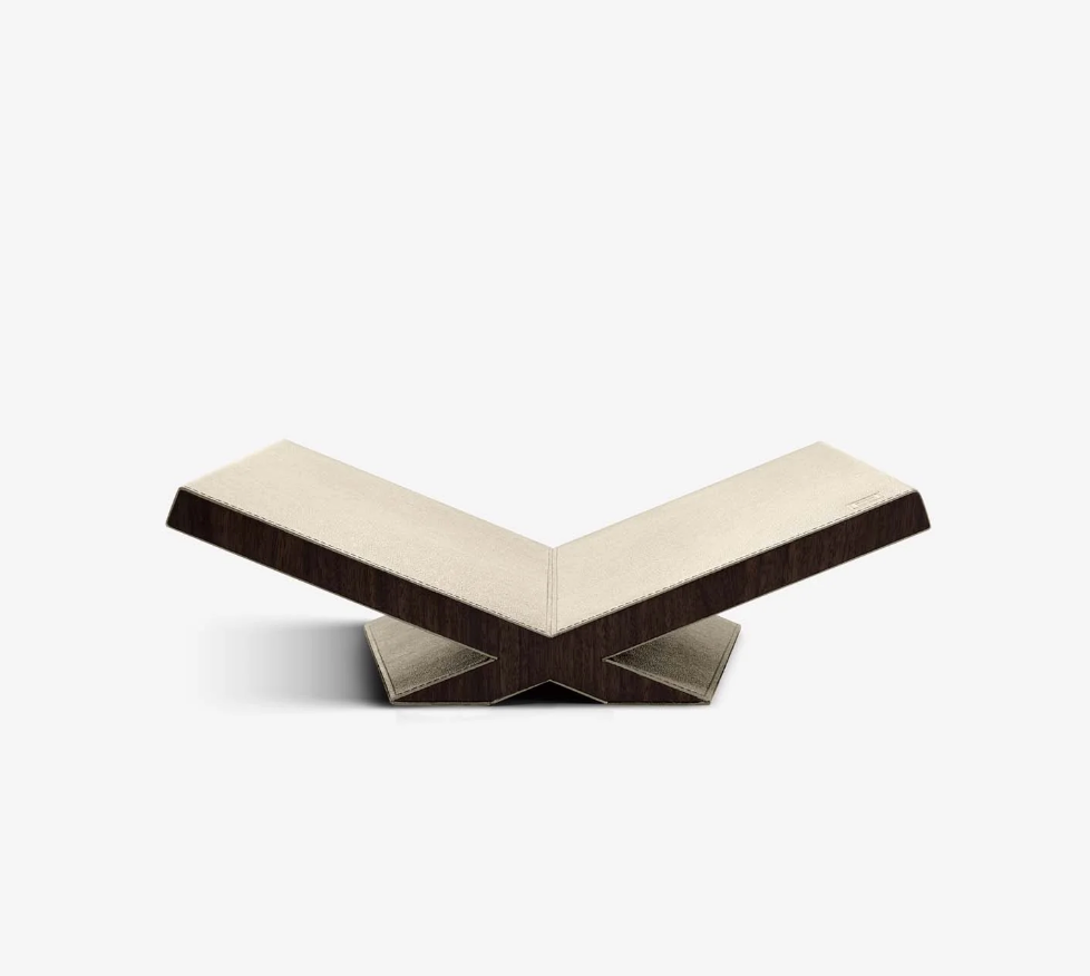 The Assouline Culture Bookstand - Stone features a modern, V-shaped design with a beige top and dark walnut sides, showcasing geometric angles and minimalist style, set against a plain white background.