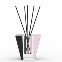 The Solar Prism Crystal Diffuser - Onyx & Rose - Elder Flower by Frave Home features a modern geometric crystal vessel with clear, pink, and black accents. Several thin black reeds stand upright against a white background, creating an elegant design perfect for infusing your space with the enchanting aroma of Elder Flower.
