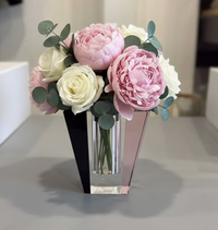 The Solar Prism Crystal Diffuser in Onyx & Rose - Elder Flower by Frave Home features a clear geometric design reminiscent of crystal, displaying pink peonies, white roses, and eucalyptus leaves, elegantly arranged on a gray surface with a softly blurred background.