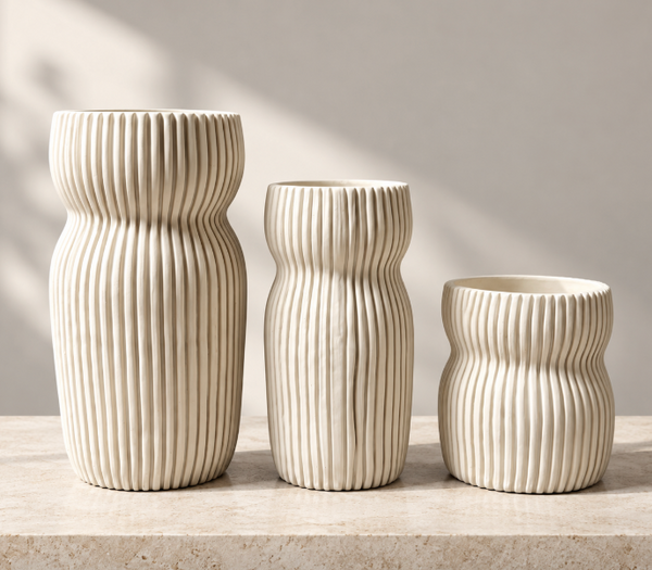 Three cream-colored, hand-sculpted Round Curvy Vase Cream vases of varying heights, each featuring a rounded, hourglass-like shape with vertical ribbed textures.