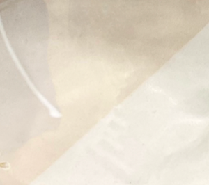 A close-up of translucent, slightly crumpled paper rests on Urban Dinnerware – Custom plates by Alex Marshall Studios, with a faint diagonal seam and white string in the upper left. The softly textured background is light.