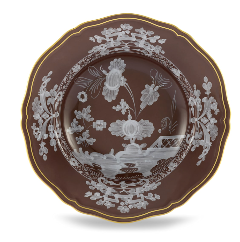The Ginori 1735 Oriente Italiano Castagna plate features a decorative brown design with scalloped edges, gold trim, and white floral patterns of large flowers and leaves on the center and border. Made in Italy.