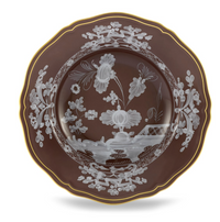 The Ginori 1735 Oriente Italiano Castagna plate features a decorative brown design with scalloped edges, gold trim, and white floral patterns of large flowers and leaves on the center and border. Made in Italy.