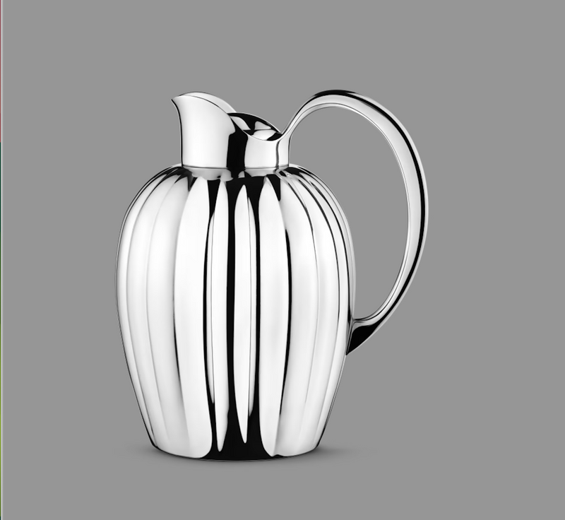 The Georg Jensen Bernadotte New Thermo Jug w/Push Stopper for coffee & tea features a polished silver finish, curved handle, and vertical ridges, showcasing modern Scandinavian style against a plain gray background.