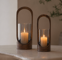 Two Modesto Hurricane - Walnut candle holders by Sagebrook Home, one tall and one short, feature oval walnut frames with glass inserts. Placed on a light surface, they’re perfect for adding modern style to your home decor.