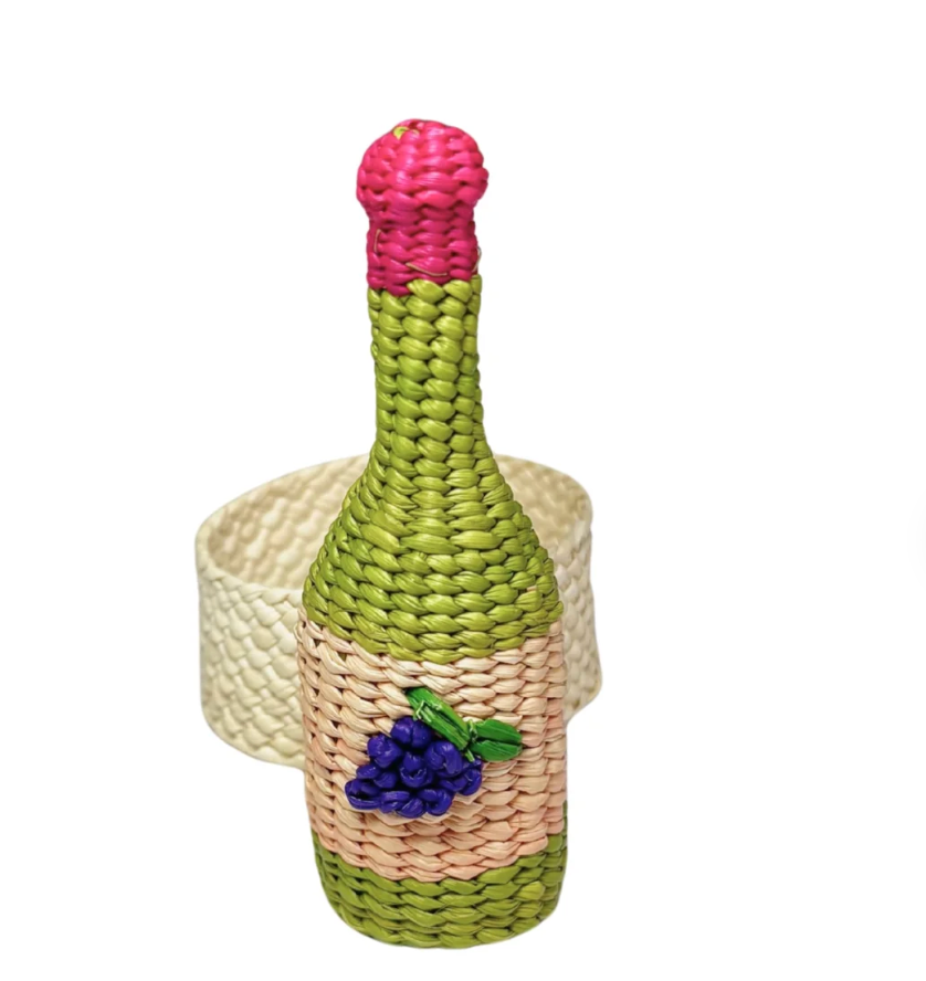 The Coro Cora Wine Napkin Ring Set of 4 - Pink features artisanal, bottle-shaped woven rings with pink tops and grape decorations, showcasing handcrafted Colombian design and adding vibrant table decor.
